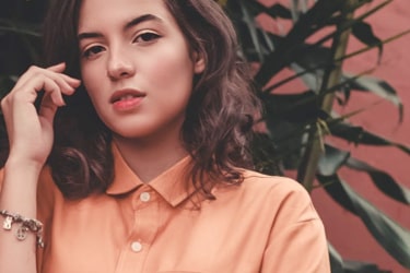 woman in peach blouse on the background with plants